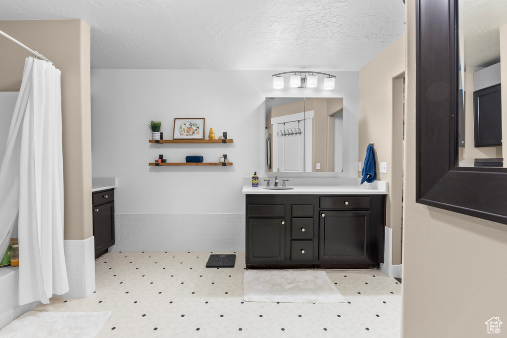 Bathroom featuring walk in shower, a textured ceiling, and vanity