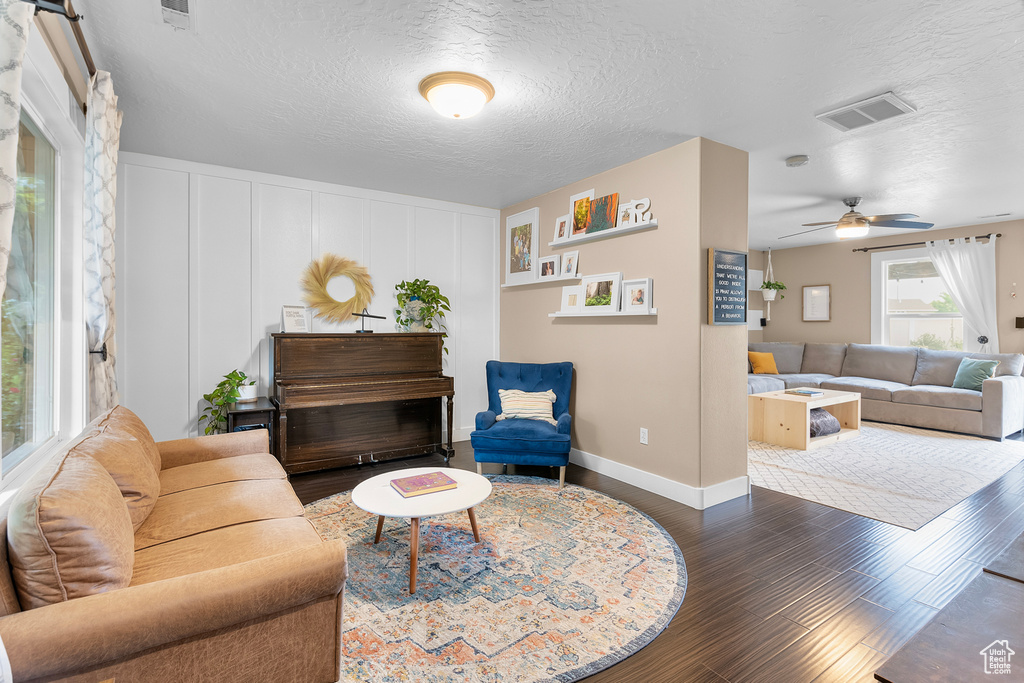 Living room with ceiling fan, dark hardwood / wood-style floors, and a textured ceiling