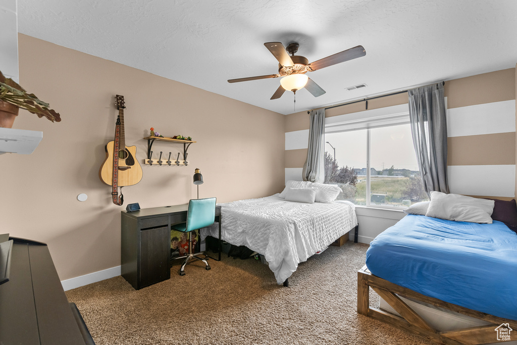 Carpeted bedroom with ceiling fan and a textured ceiling