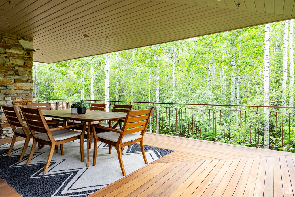 Wooden terrace with outdoor dining area and a forest view