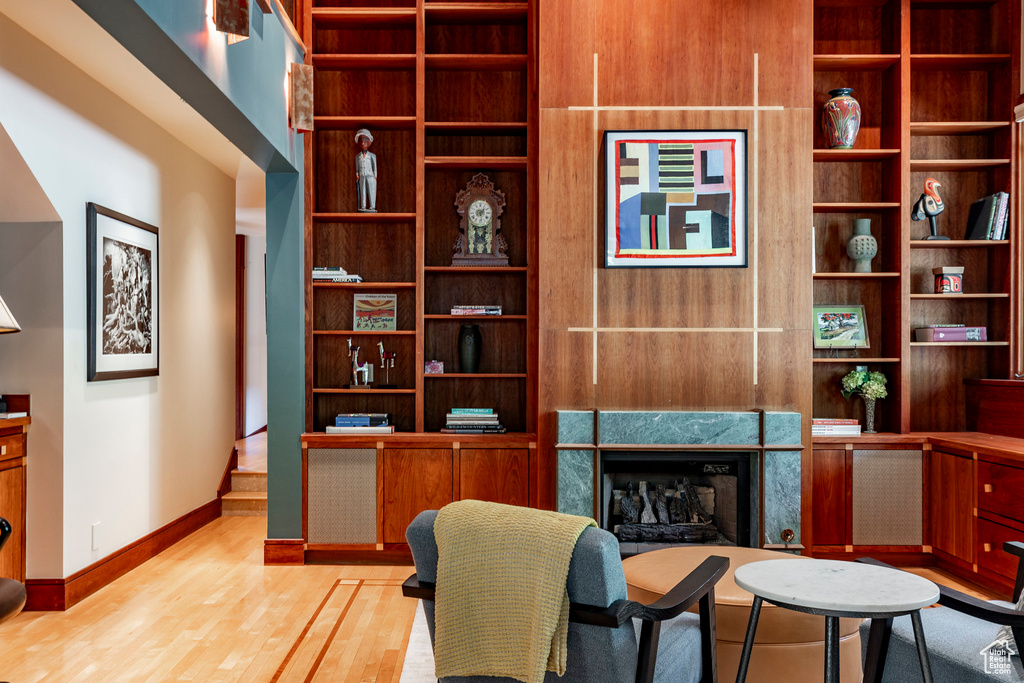 Living area featuring a fireplace, stairway, baseboards, and wood finished floors