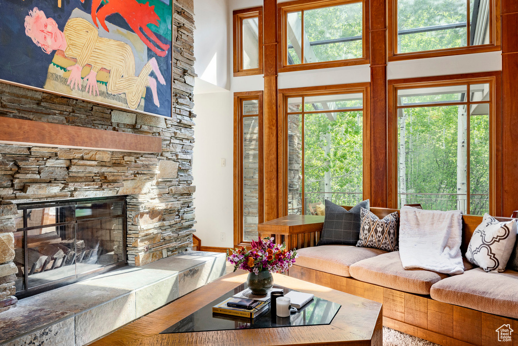 Living room featuring a high ceiling, plenty of natural light, and a stone fireplace
