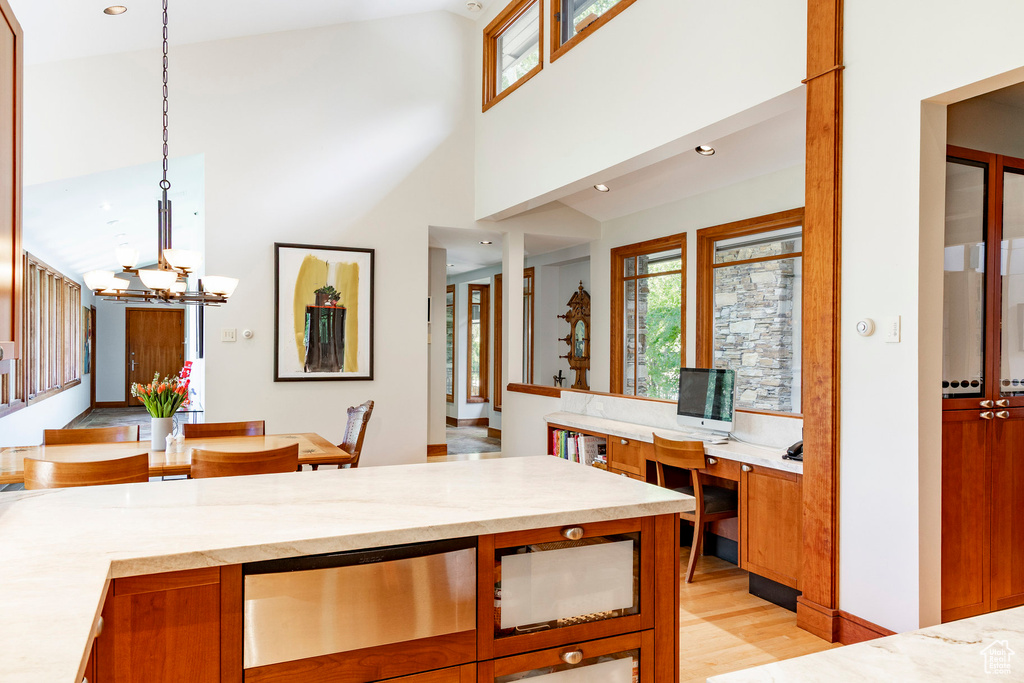 Kitchen with a chandelier, healthy amount of natural light, decorative light fixtures, light wood-style floors, and a high ceiling