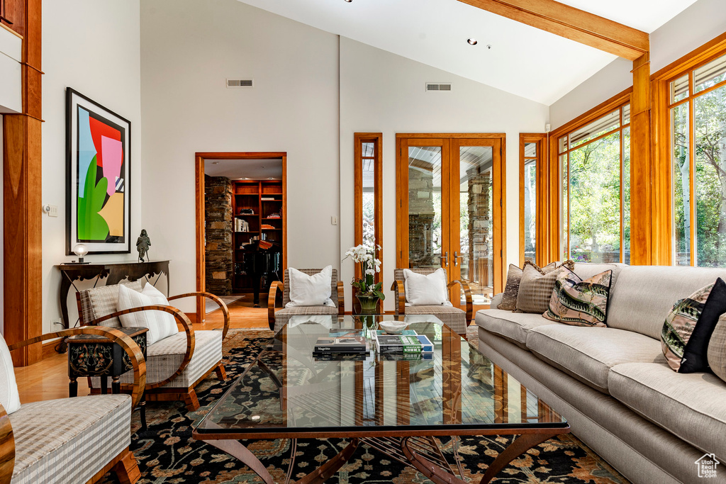 Living room with high vaulted ceiling, french doors, visible vents, and wood finished floors