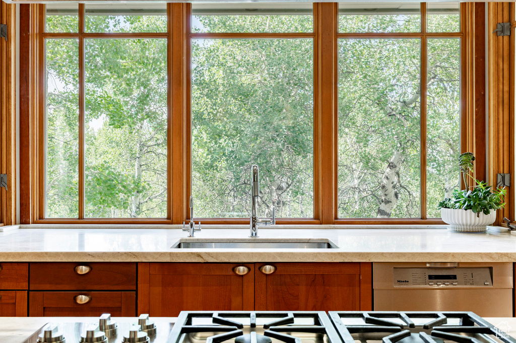Kitchen with plenty of natural light, brown cabinets, and light stone counters