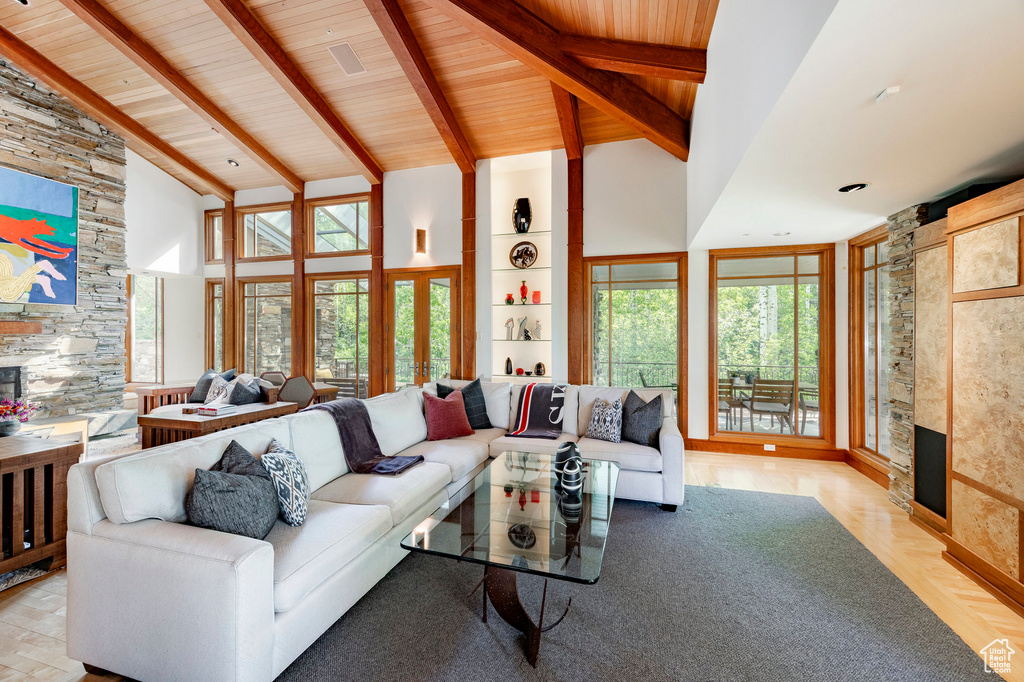 Living area featuring high vaulted ceiling, a stone fireplace, and a wood ceiling with exposed beams