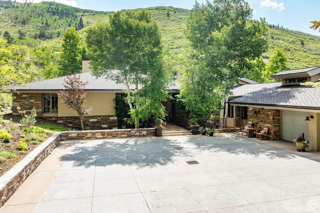 View of front of house featuring stone siding, a mountain view, and stucco siding