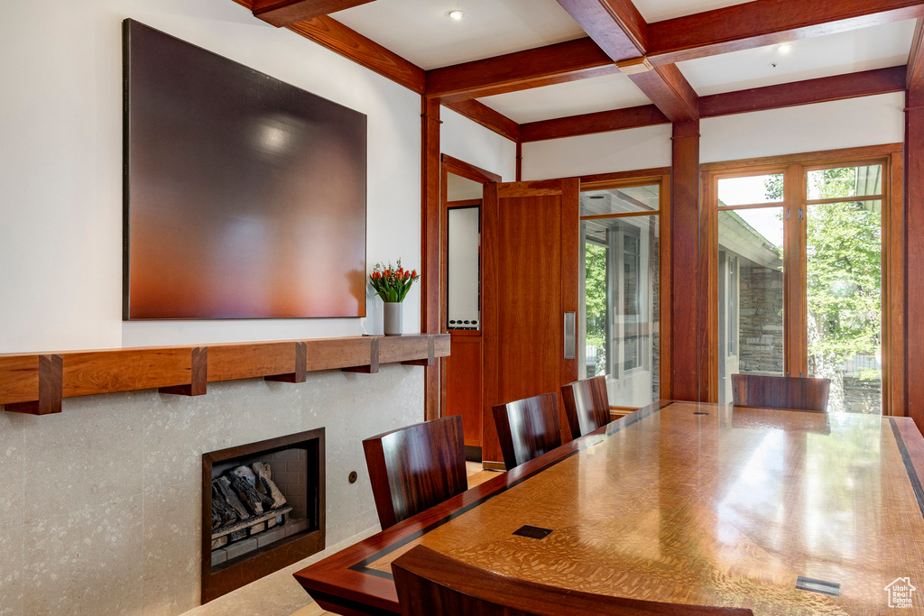 Dining room with coffered ceiling, plenty of natural light, beamed ceiling, and a fireplace