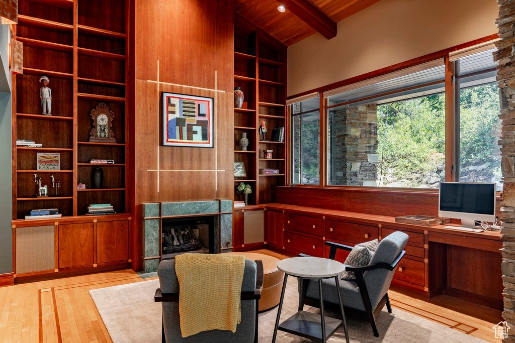 Home office with a fireplace, wooden ceiling, light wood-style floors, and built in shelves