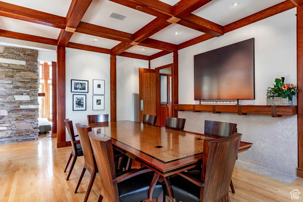 Dining area with light wood-style floors, visible vents, beam ceiling, and coffered ceiling
