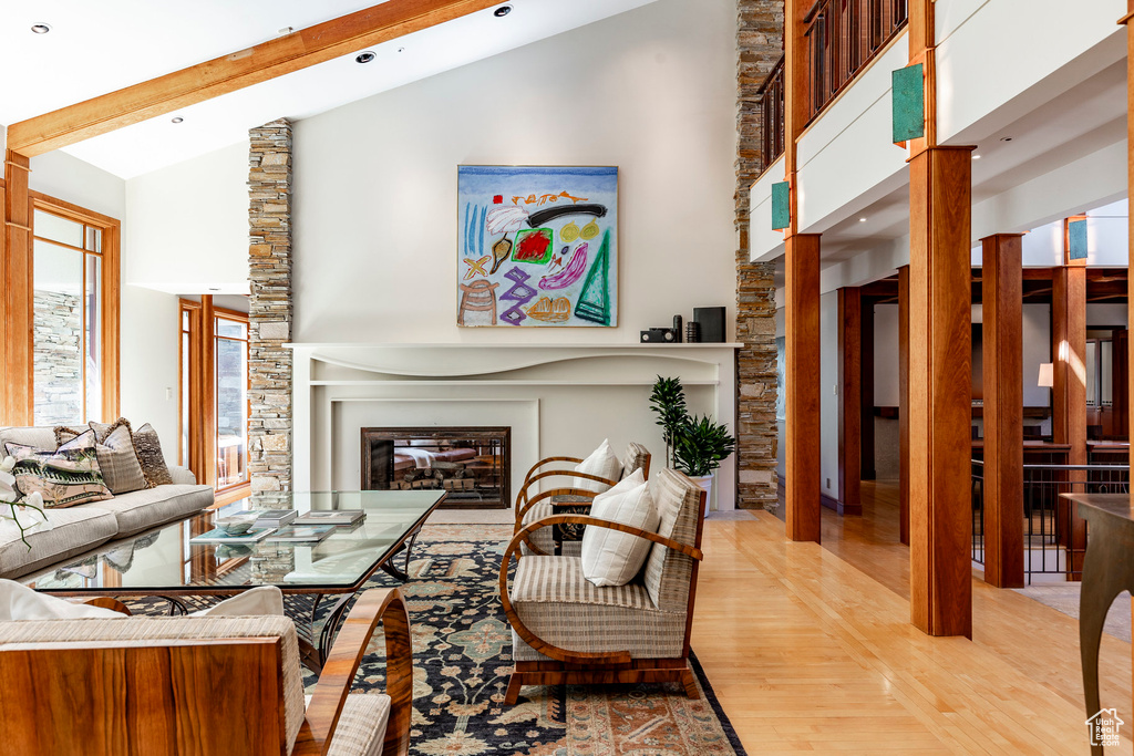 Living room with wood finished floors, a glass covered fireplace, high vaulted ceiling, and recessed lighting