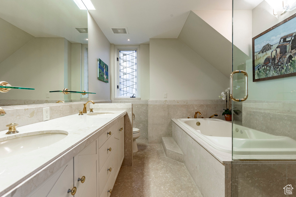 Bathroom with double vanity, a garden tub, visible vents, and a sink