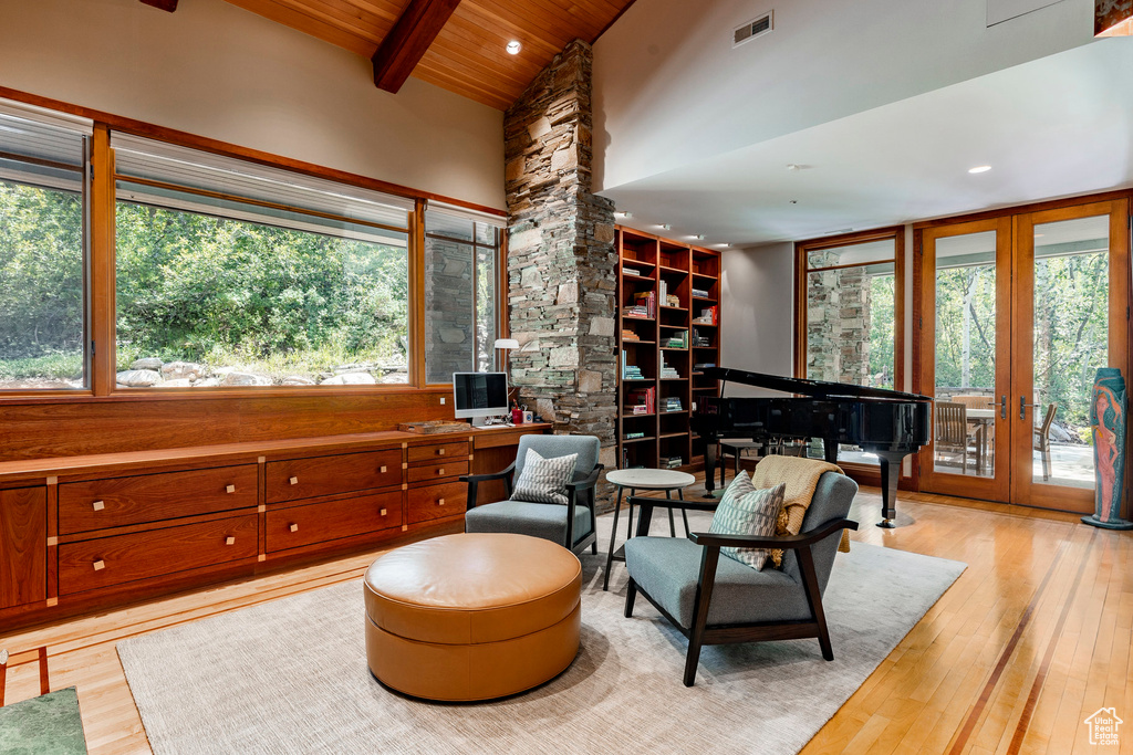 Living area featuring wooden ceiling with exposed beams, plenty of natural light, light wood-style floors, high vaulted ceiling, and french doors