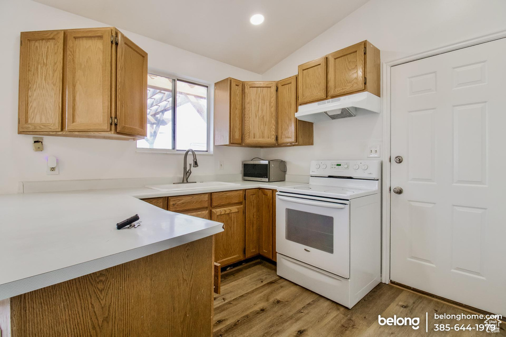 Kitchen with light hardwood / wood-style flooring, electric range, sink, and vaulted ceiling