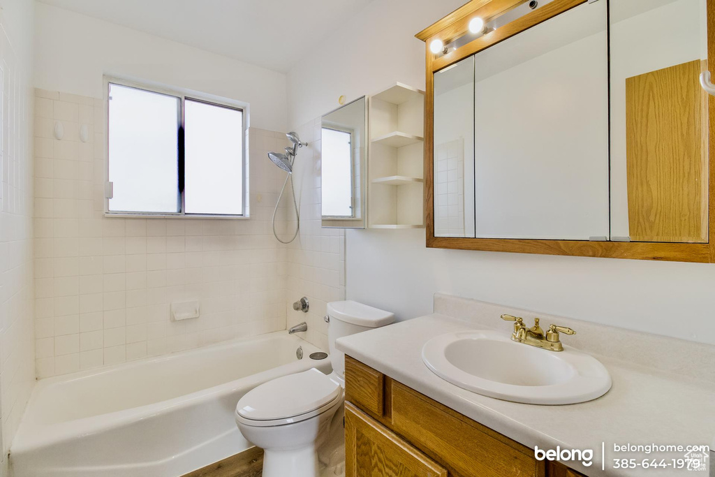 Full bathroom featuring toilet, tiled shower / bath combo, hardwood / wood-style flooring, and vanity