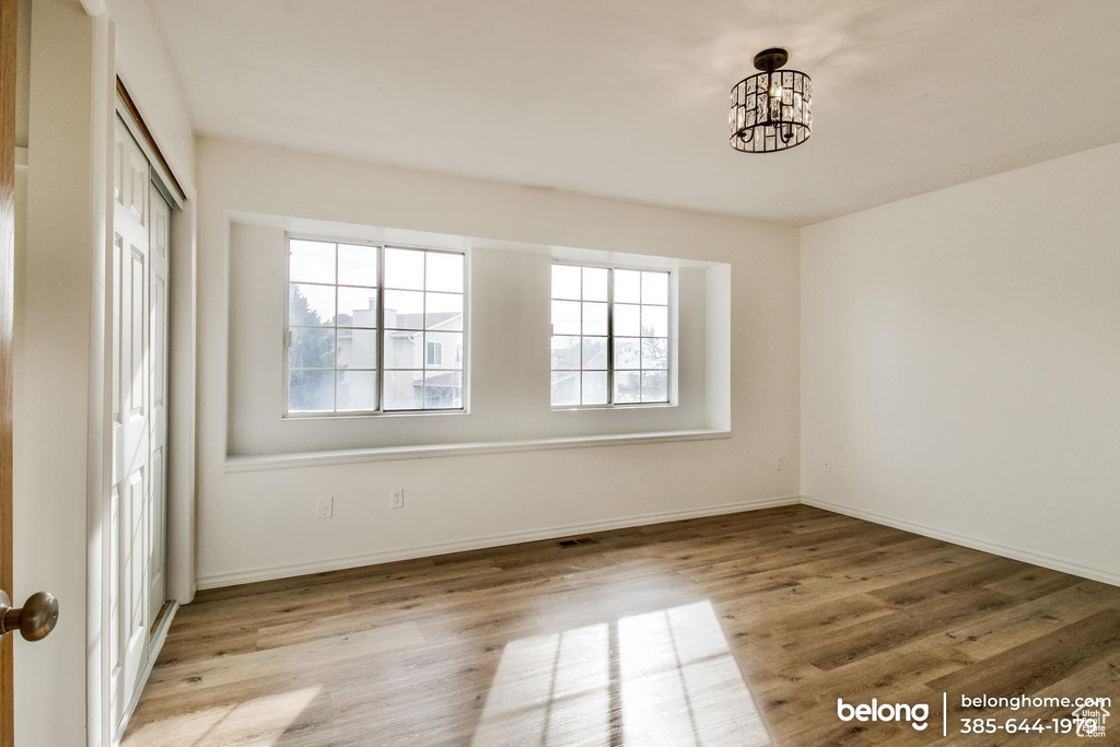 Empty room featuring plenty of natural light, a notable chandelier, and light hardwood / wood-style floors