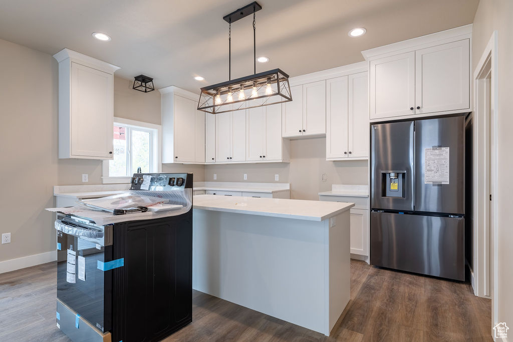 Kitchen with stainless steel fridge, electric range, a center island, and white cabinetry