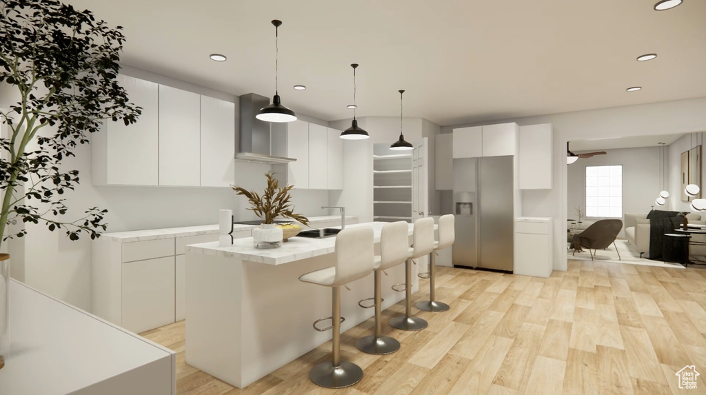 Kitchen featuring light wood-type flooring, a kitchen island with sink, stainless steel fridge with ice dispenser, white cabinets, and hanging light fixtures