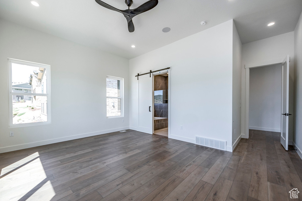 Interior space with a barn door, ceiling fan, and dark hardwood / wood-style flooring