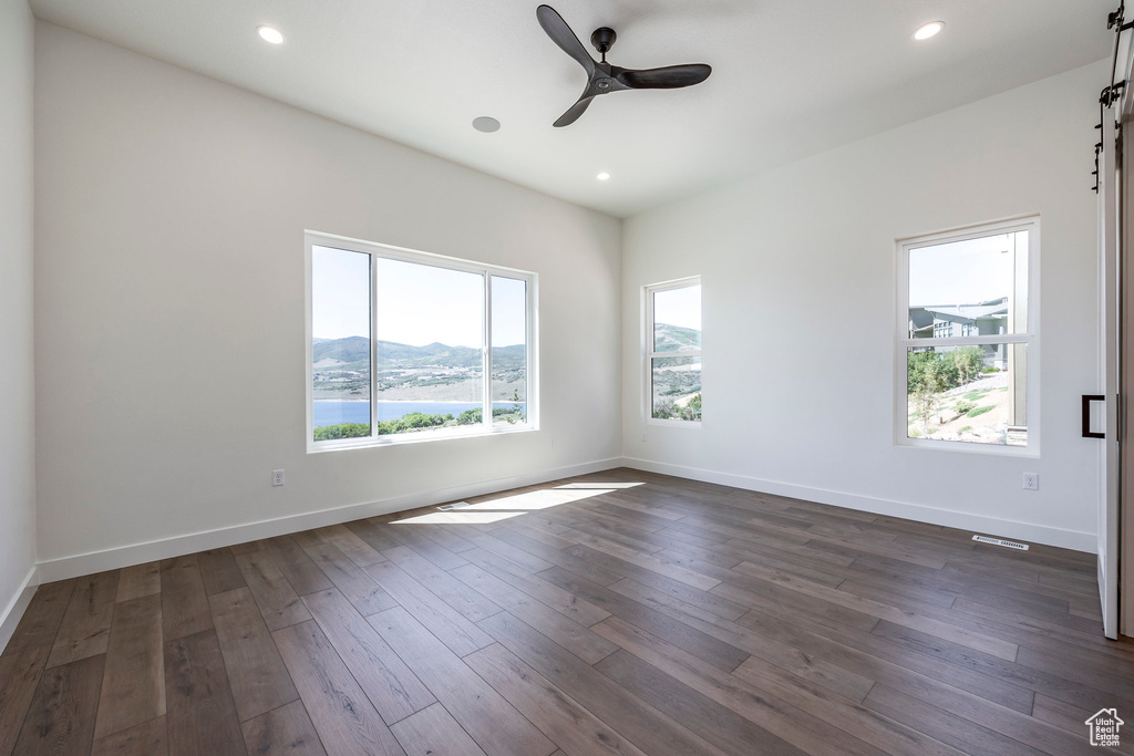 Unfurnished room with ceiling fan, a wealth of natural light, dark hardwood / wood-style floors, and a mountain view