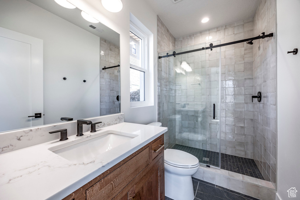 Bathroom with a shower with door, vanity, toilet, and tile patterned floors