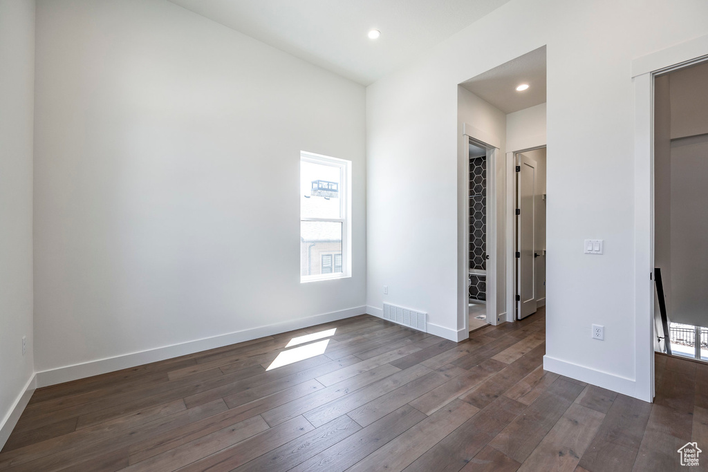 Unfurnished bedroom featuring multiple windows, a walk in closet, dark hardwood / wood-style flooring, and a closet