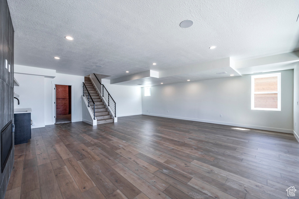 Unfurnished living room featuring dark hardwood / wood-style flooring and a textured ceiling