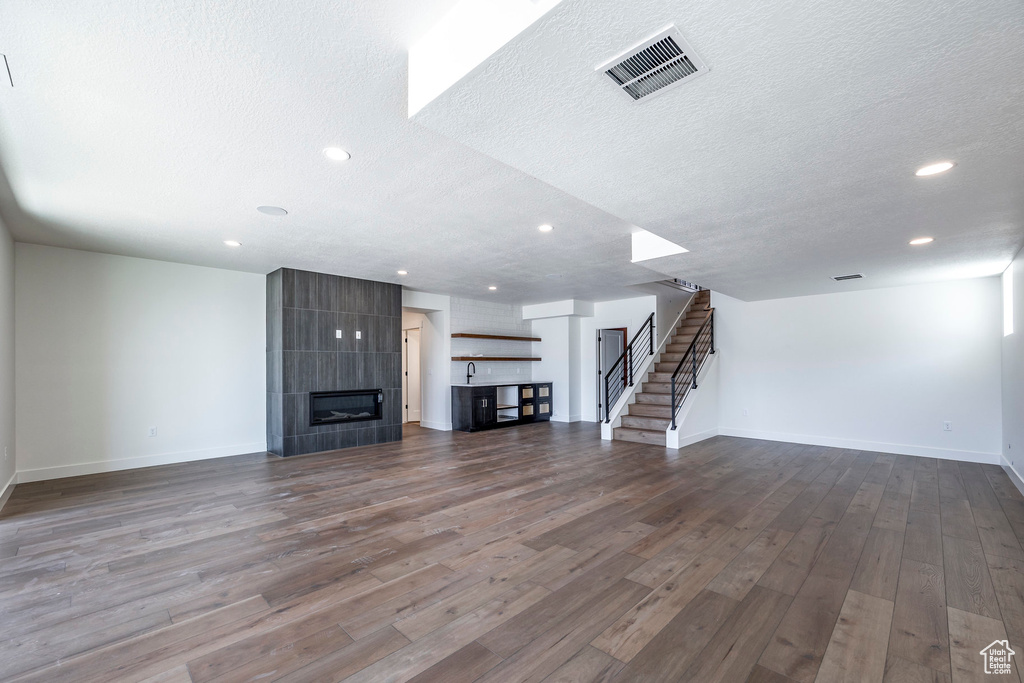 Unfurnished living room featuring a fireplace, dark hardwood / wood-style flooring, sink, and a textured ceiling