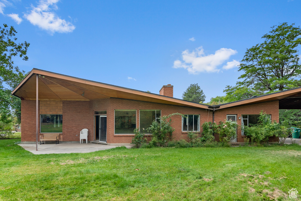 Rear view of property featuring a lawn and a patio area