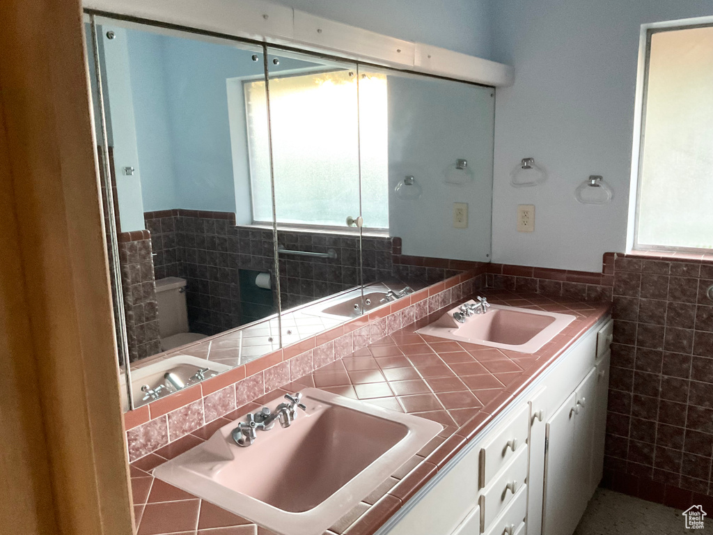 Bathroom with tile walls, vanity, and toilet