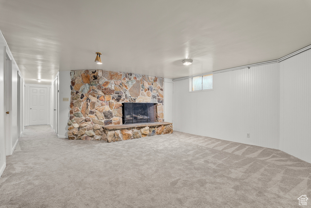 Unfurnished living room featuring a stone fireplace and light colored carpet