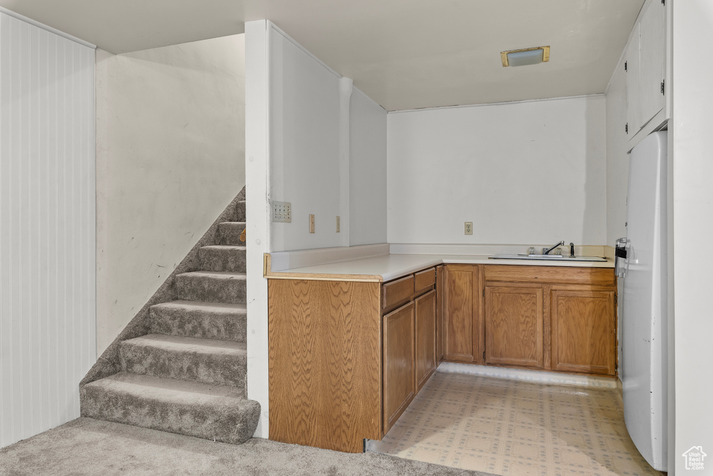 Kitchen with sink, light carpet, and white refrigerator