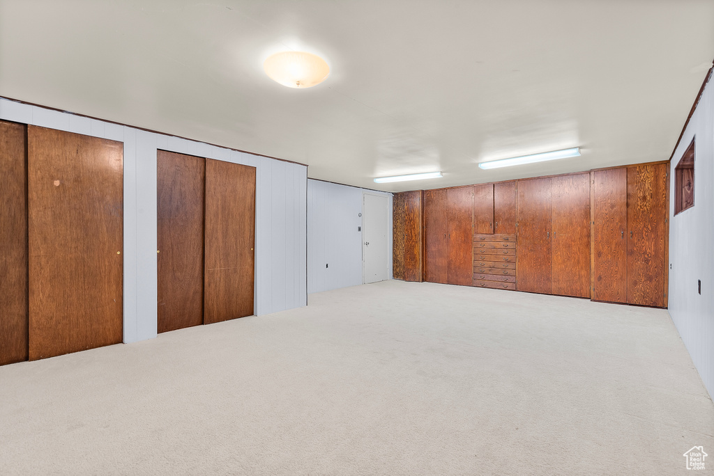 Bedroom with two closets, wood walls, and carpet floors