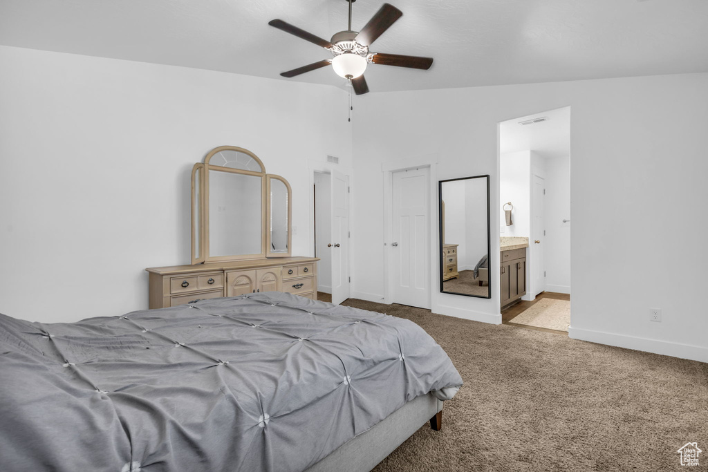 Bedroom featuring vaulted ceiling, light colored carpet, ensuite bathroom, and ceiling fan