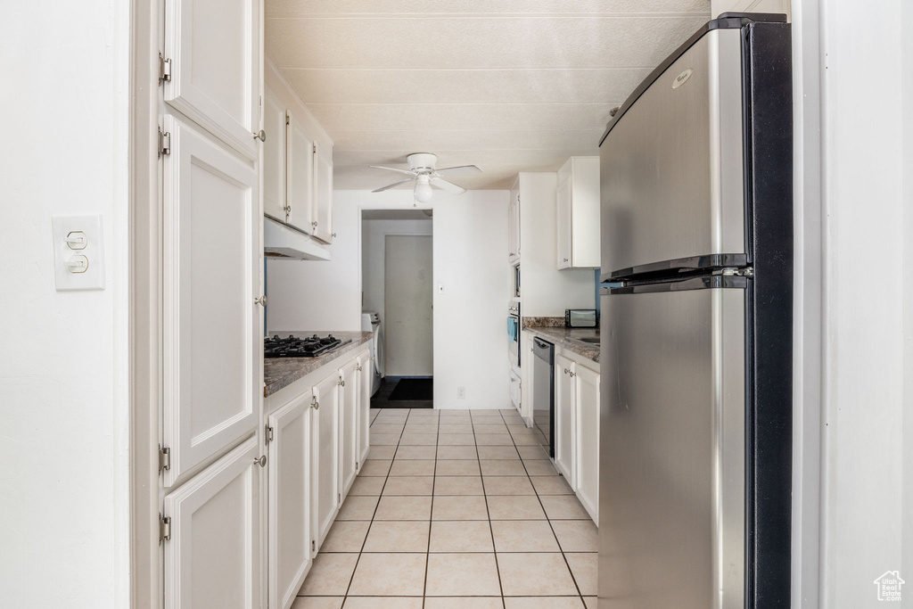 Kitchen featuring light tile patterned floors, light stone counters, ceiling fan, appliances with stainless steel finishes, and white cabinets