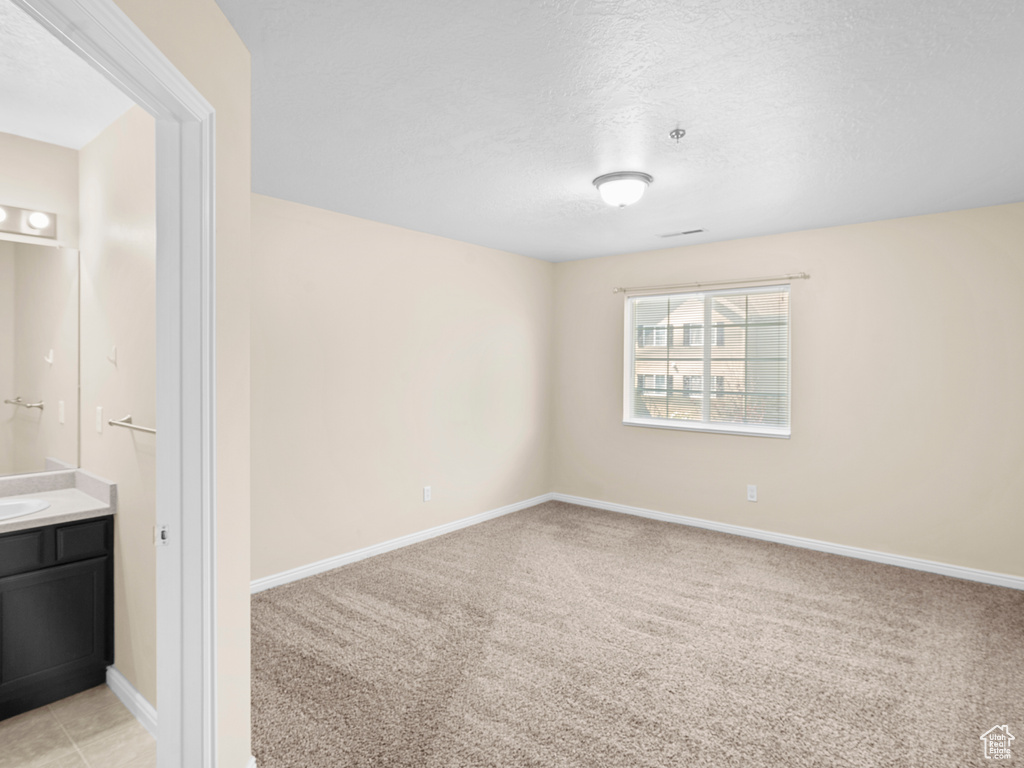 Spare room with a textured ceiling and light colored carpet