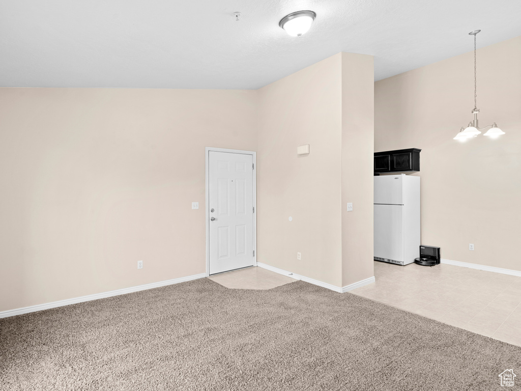 Empty room featuring carpet, an inviting chandelier, and high vaulted ceiling