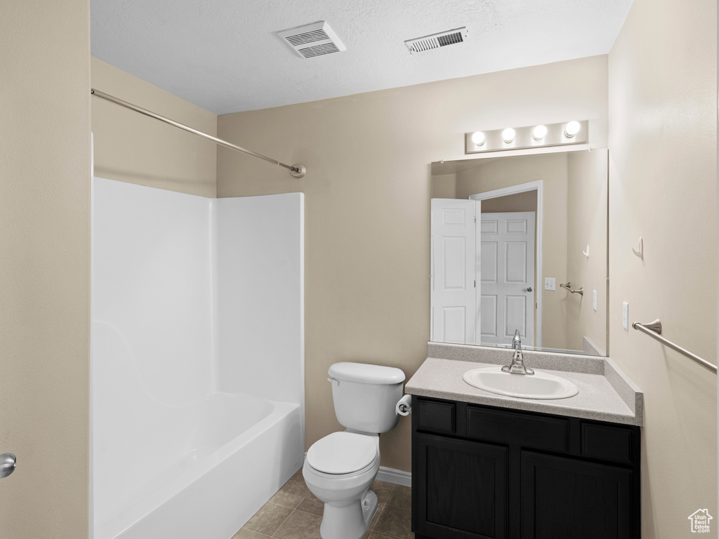 Full bathroom featuring shower / bathtub combination, tile patterned floors, toilet, vanity, and a textured ceiling