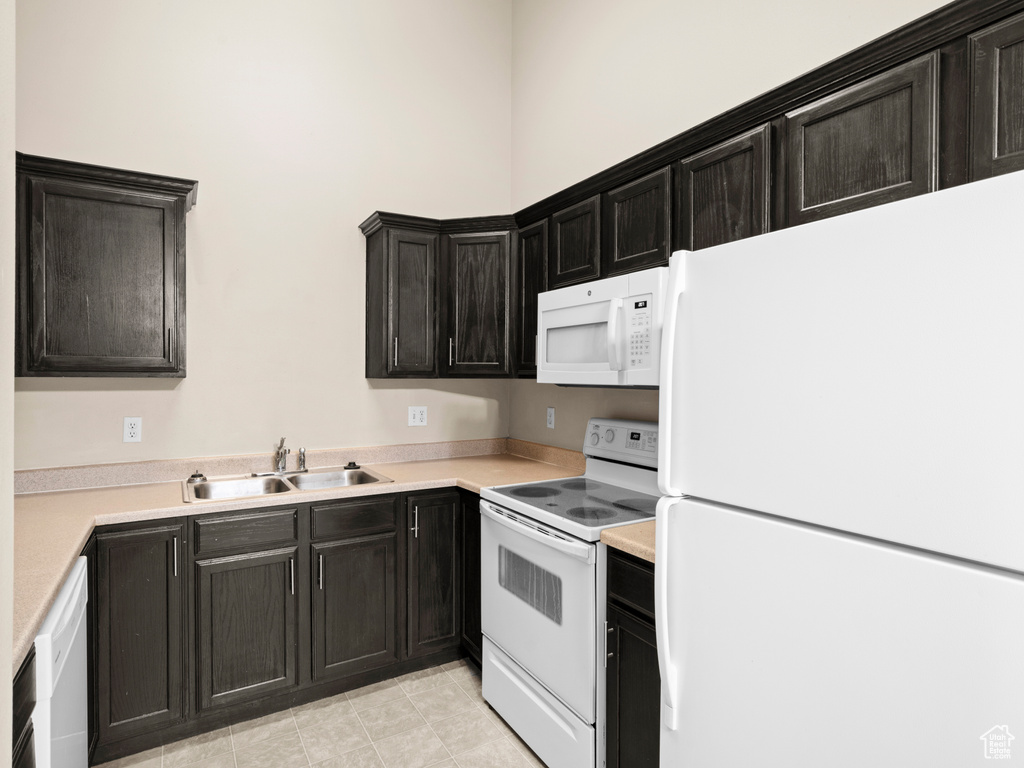 Kitchen with sink, light tile patterned floors, and white appliances