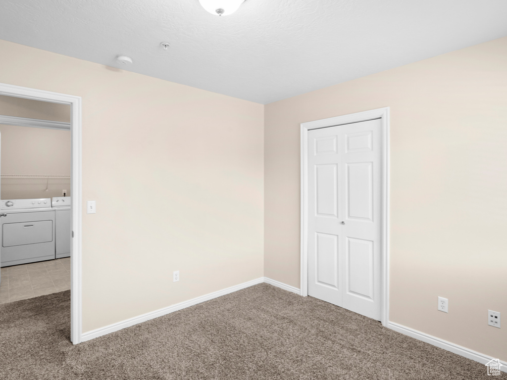 Unfurnished bedroom with separate washer and dryer, a closet, and carpet floors