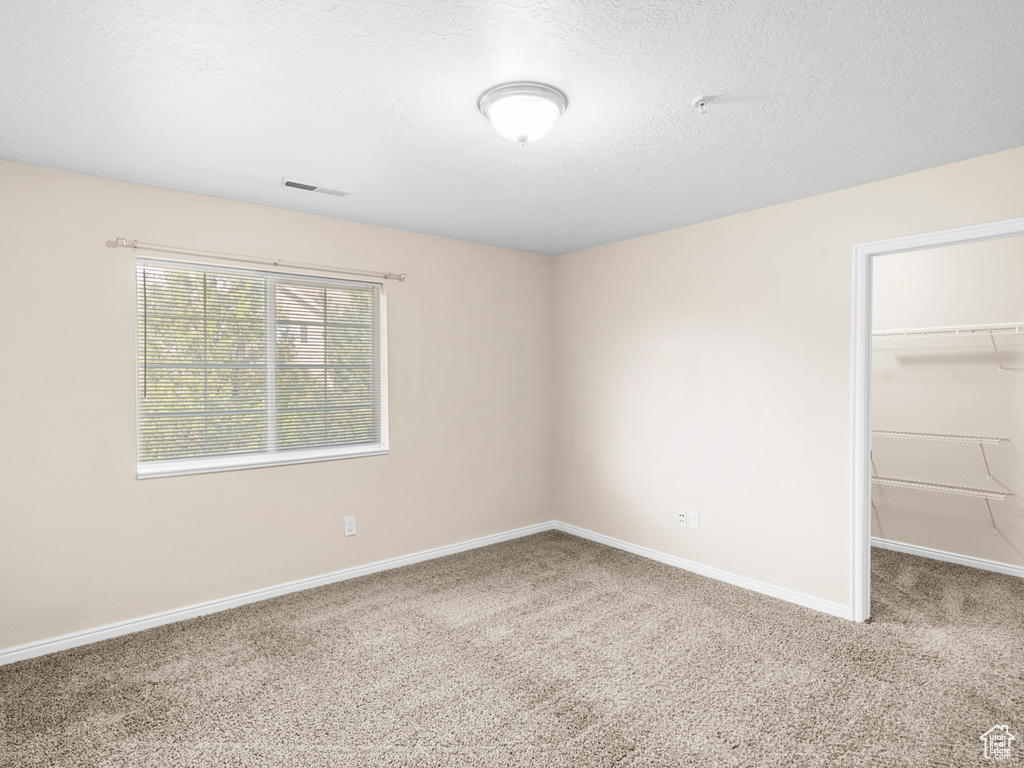 Carpeted spare room with a textured ceiling