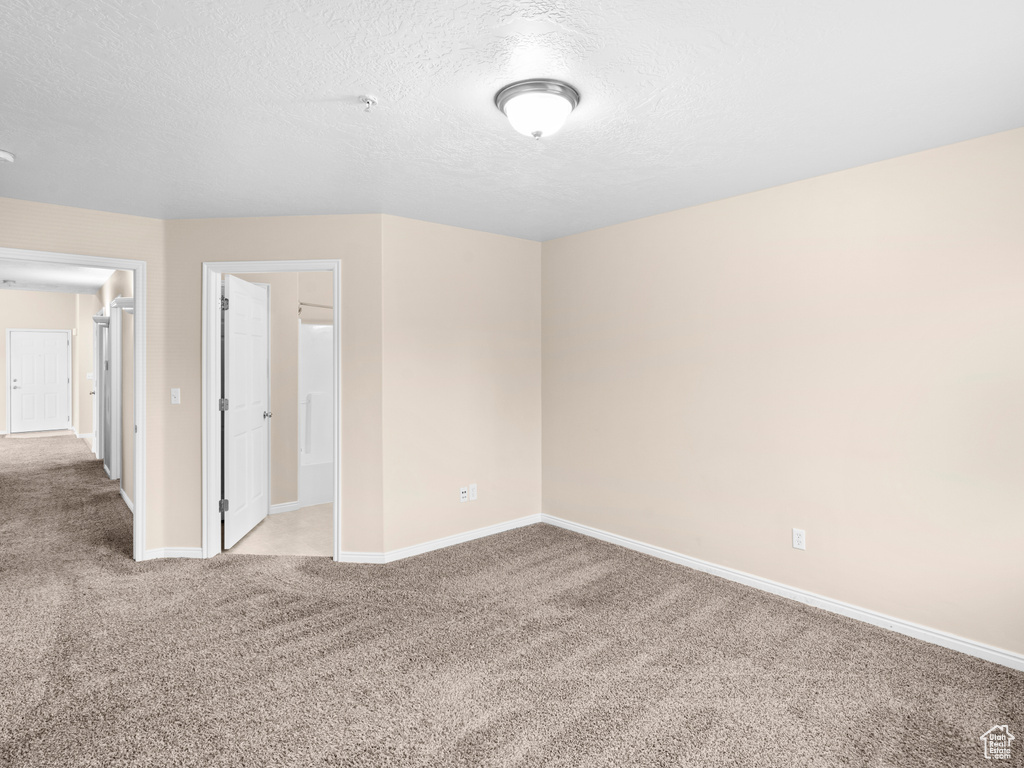 Spare room with a textured ceiling and light colored carpet