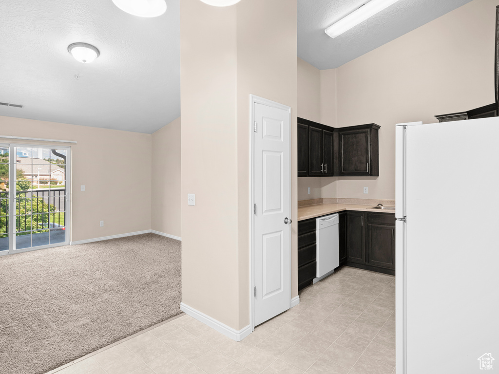 Kitchen featuring a textured ceiling, light colored carpet, and white appliances