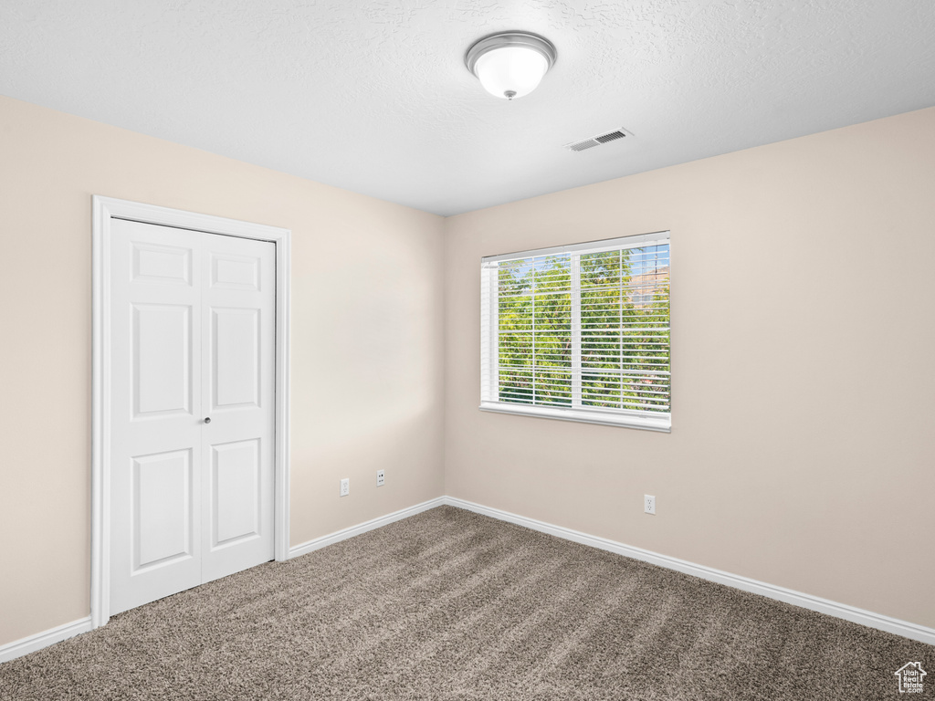 Unfurnished bedroom featuring a closet, a textured ceiling, and carpet flooring