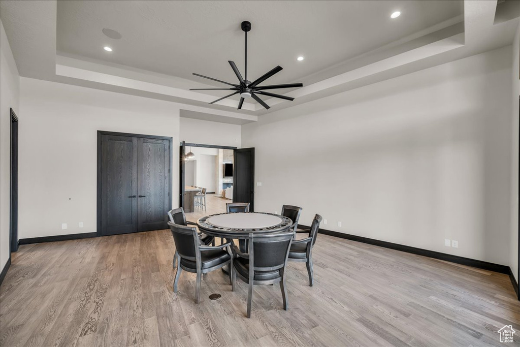 Dining area featuring a tray ceiling, light hardwood / wood-style flooring, and ceiling fan