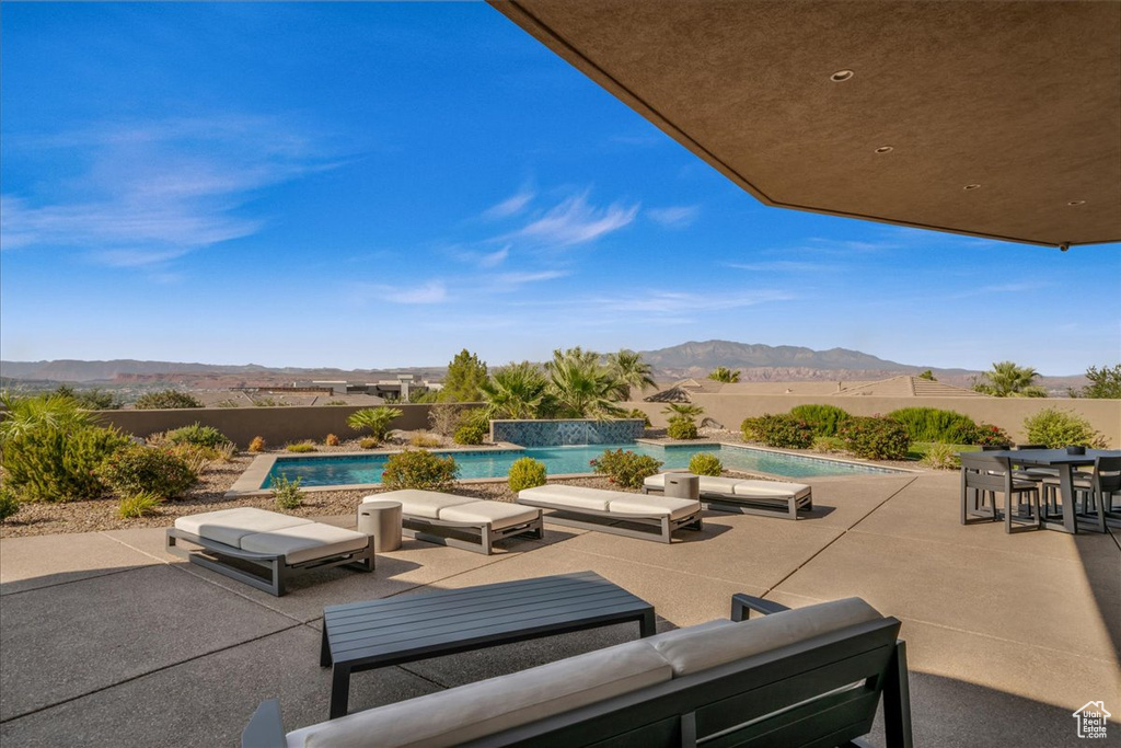 View of patio / terrace featuring a fenced in pool, a mountain view, outdoor lounge area, and pool water feature