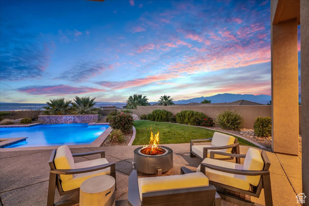 Pool at dusk with a patio, a mountain view, and an outdoor living space with a fire pit