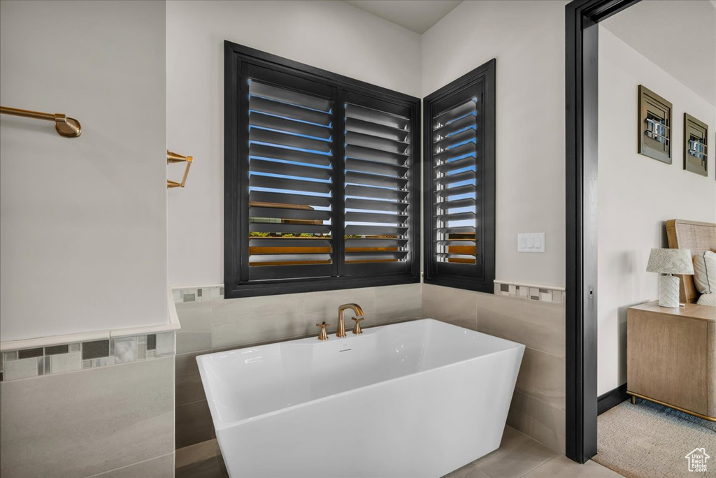 Bathroom with a tub to relax in, tile walls, and tile patterned flooring