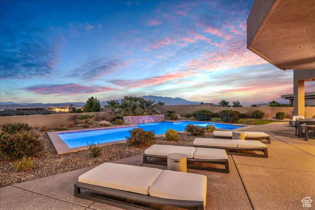 Pool at dusk featuring a patio