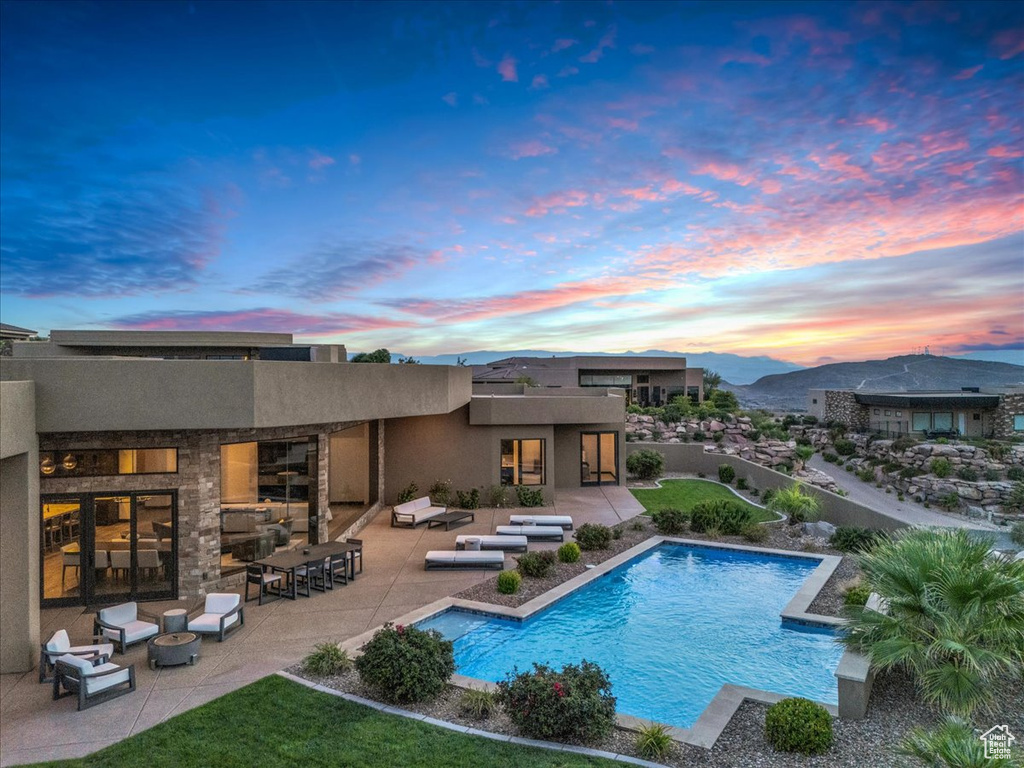 Pool at dusk with a mountain view, an outdoor hangout area, and a patio